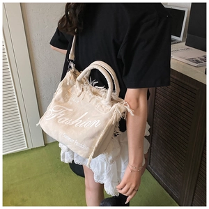Detail of beige canvas tote with tassel edges and 'Summer Paradise' printed text
