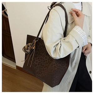 Detailed macro view of large leopard print tote bag with brown straps and fringe charm