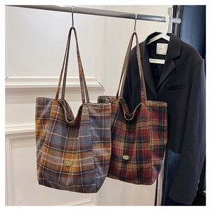 Detailed macro view of vintage plaid tote bags with handmade metal logo and wool texture