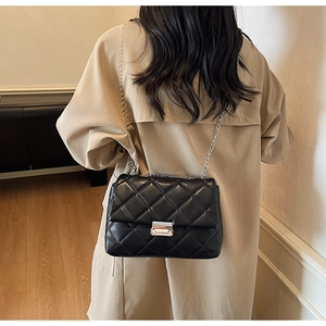 Detail shot of the elegant black quilted crossbody bag with a silver chain and metal lock