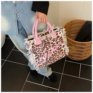 Detail of leopard print tote bag with white fringe tassels and pink fashion handles