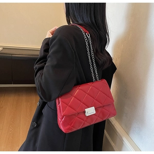 Close-up of a red quilted leather shoulder bag with a silver metallic rectangular lock