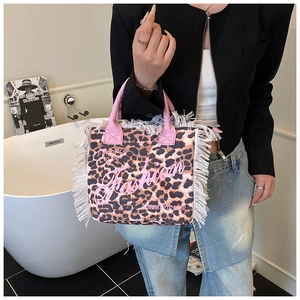Detail of leopard print tote bag with pink handles and white fringe trim and artwork