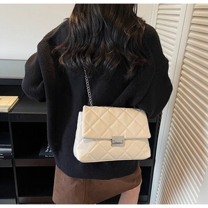 Detail of beige quilted leather crossbody bag with silver twist lock and chain strap