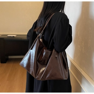Detailed side view of a large vintage dark brown glossy tote bag on a female model