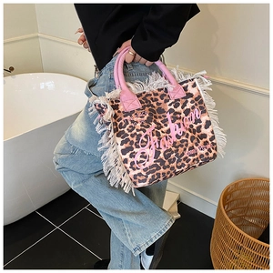 Close-up of leopard print tote bag with pink handles and stylish white fringe tassels