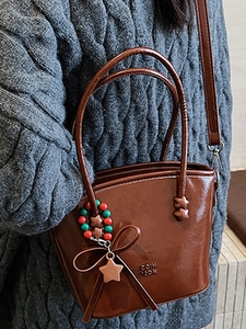 Dark brown glossy bucket handbag with star charms and crossbody strap for daily commute
