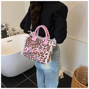 Detail of leopard print canvas bag with pink leather handles and bohemian fringe trim