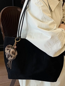 Large black suede tote bag with leopard print pompom charm and gold hardware on shoulder