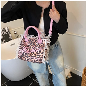 Detail of leopard print tote bag with pink tassels and fashion lettering on shoulder