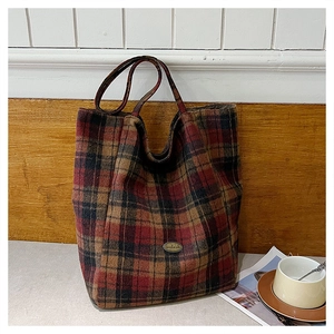 Detailed close-up of retro plaid tote bag with handmade metal logo and wool texture