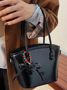 Fashionable black patent leather tote bag with bow detail and retro star charm accessory