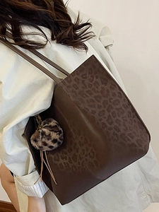 Brown leopard print large tote bag for women with a plush keychain on beige trench coat