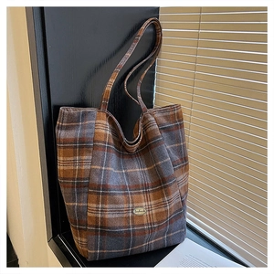 Detail showing the wool texture and 'handmade' oval label of the plaid tote bag