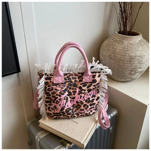 Detail of leopard print canvas bag with pink handles, fringe trim, and Fashion text