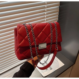 Detail of red quilted leather crossbody bag with silver metal chain and rectangle lock