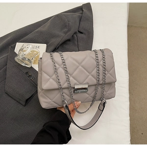 Close-up of quilted grey crossbody bag featuring a silver metal twist lock and chain strap