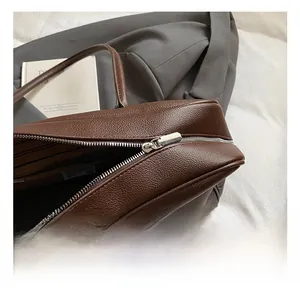 Detail of silver metal zipper and dark brown lychee grain leather on tote bag