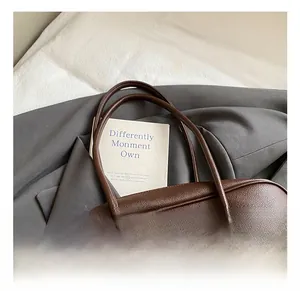 Detail of dark brown tote bag with litchi texture and elegant metal leather charm