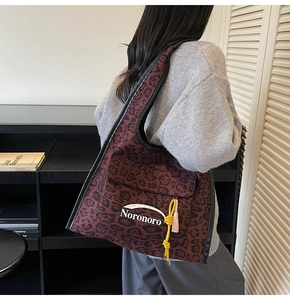 Détail du sac cabas en toile imprimé léopard avec logo Noronoro et pompon jaune