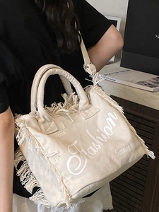 Minimalist off-white canvas tote bag with fringe tassels and fashion lettering print
