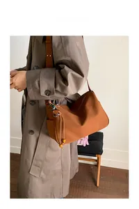 Close-up of brown suede hobo bag with wide strap styled with matching autumn trench coat
