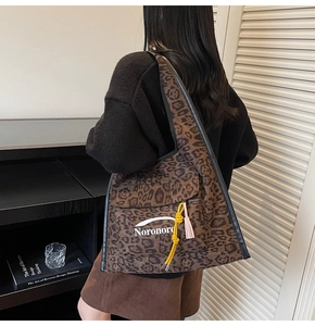 Detail of leopard print canvas tote bag with hanging tassels on model's shoulder