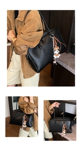 Detail of black pebbled leather tote bag featuring a cute schnauzer plush keychain accessory