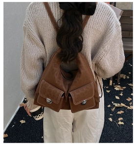 Detail of dark brown backpack with white stitching and external flap pockets