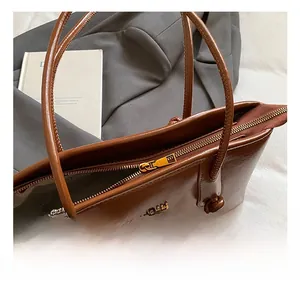 Close-up of refined gold-tone metal hardware and zipper on a brown vintage leather tote