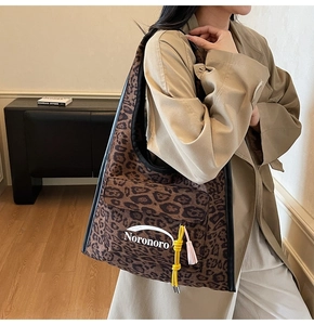 Detail of leopard print canvas tote bag with Noronoro logo and colorful tassel charm
