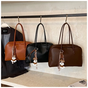 Close-up of caramel, black, and coffee leather tote bags with dog charms on a display rack