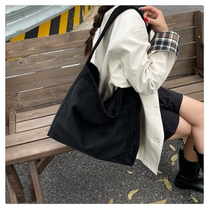 Foto all'aperto di una borsa tote nera in velluto a coste indossata da una modella