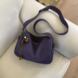 Detail of deep purple suede-like bag with decorative tassel and adjustable wide shoulder strap