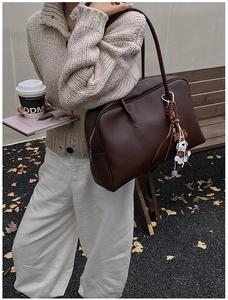 Detail of dark brown lychee pattern leather tote bag with a cute white puppy pendant