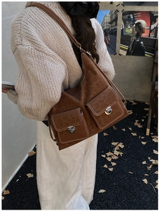 Close-up of brown vintage large crossbody bag with white stitching and front pockets