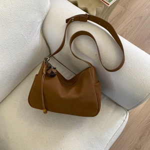 Close-up of caramel faux suede hobo bag with a decorative wooden bead flower charm