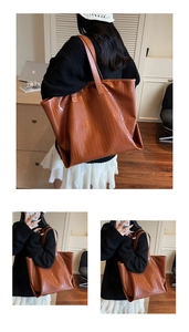 Detail of a large brown tote bag featuring premium crocodile texture and long shoulder straps