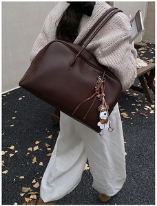 Deep brown litchi pattern leather tote bag with a cute dog charm on a soft autumn background