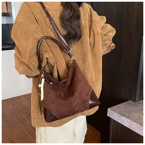 Detail of deep brown faux suede tote bag with shiny leather strap and chic bead charm decoration