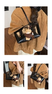Close-up of black glossy patent leather tote bag with a cute brown bear charm