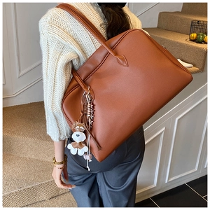 Brown faux leather tote bag detail with cute dog charm keychain on minimalist background