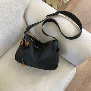 Close-up of a black hobo bag on a sofa showing soft texture and contrast floral charm