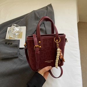 Detail of burgundy leopard embossed bucket bag with gold hardware and bead charm