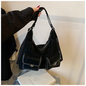 Detail of hobo bag with leopard embossing, dual front pockets, and contrast white stitching