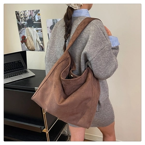 Dettaglio di una grande borsa tote in pelle scamosciata marrone portata a spalla per ufficio