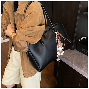 Close-up of black lychee-grain leather tote bag with a cute cartoon dog charm on shoulder