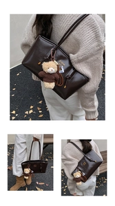 Detail of vintage brown leather tote bag with gold lettering and cute bear charm