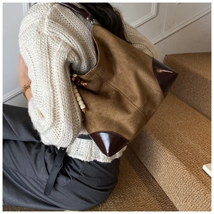 Close-up of brown suede hobo bag with deep brown leather trim and beaded tassel detail