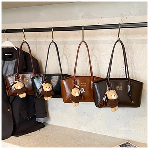 Detail of minimalist tote bags in four colors with cute teddy bear pendants on a rack